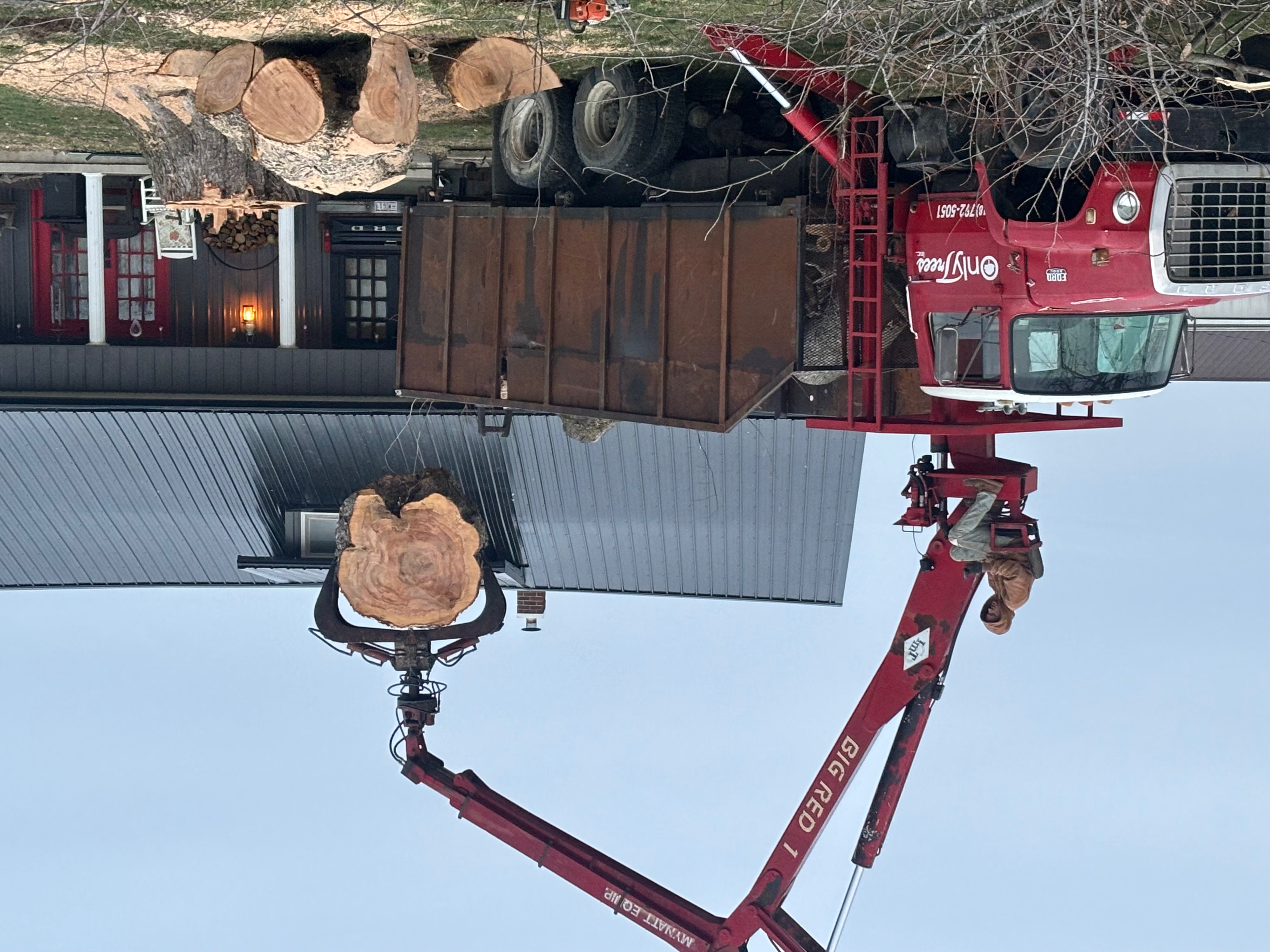 Big Red 1 — Only Trees Inc red crane grapple holding a massive log section during a tree removal job